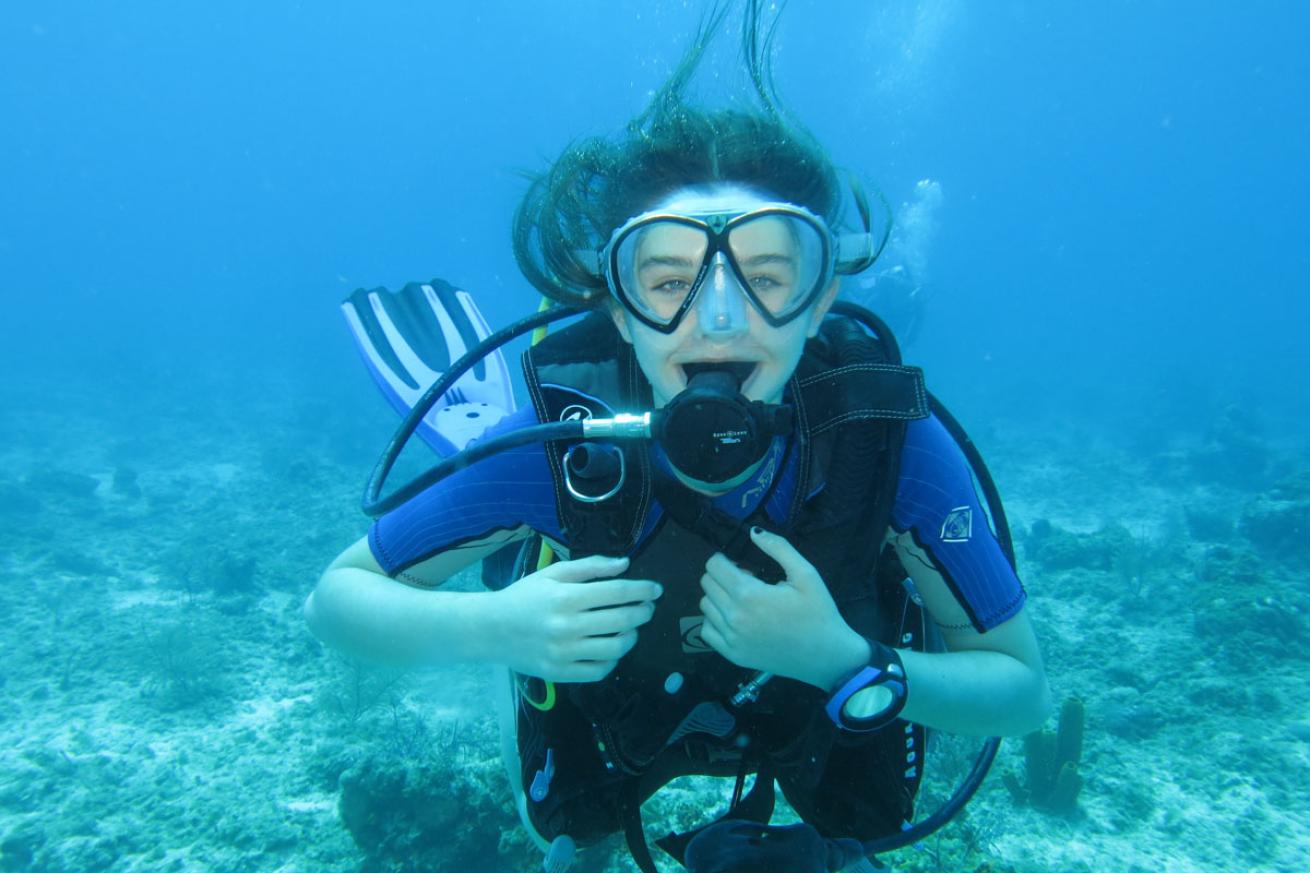 Young female scuba diving looking at camera