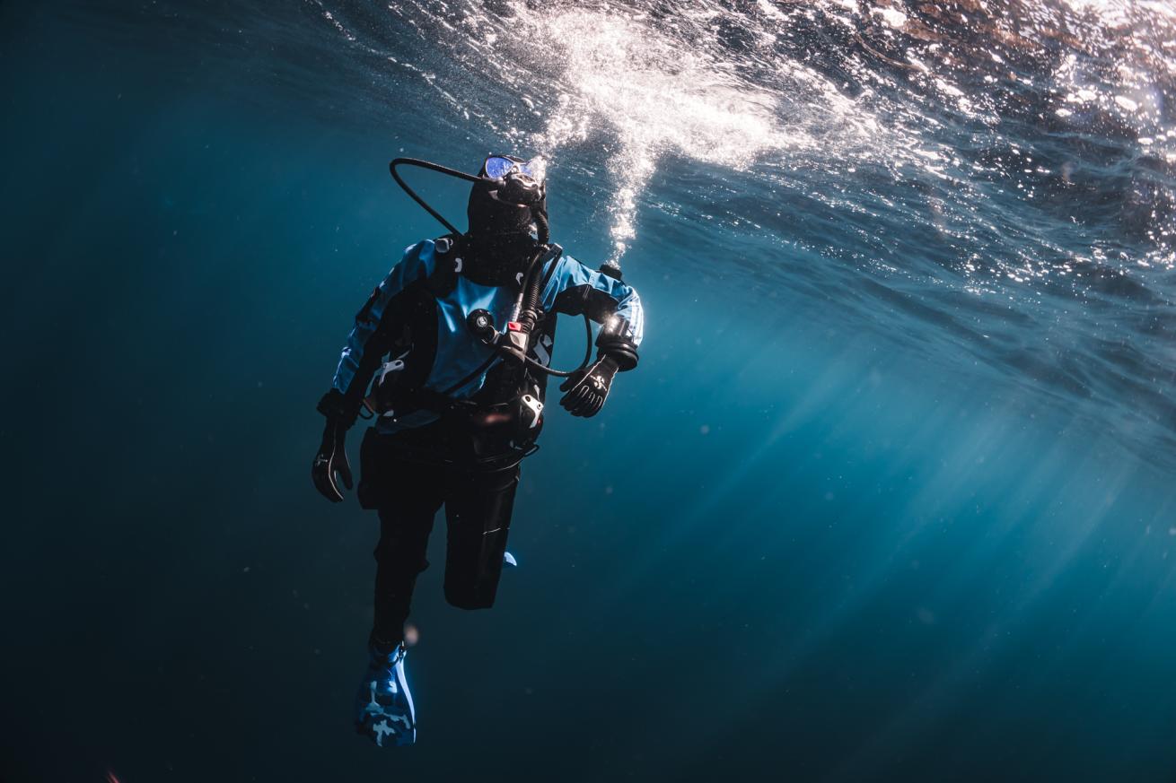 a diver in a drysuit venting gas