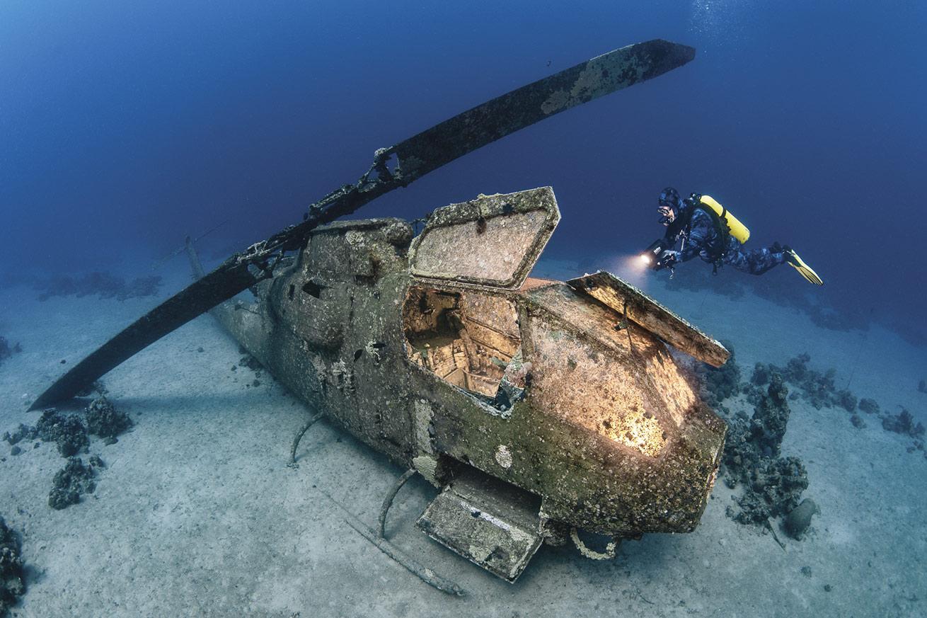 a scuba diver swims above a helicopter wreck in Aqaba, Jordan