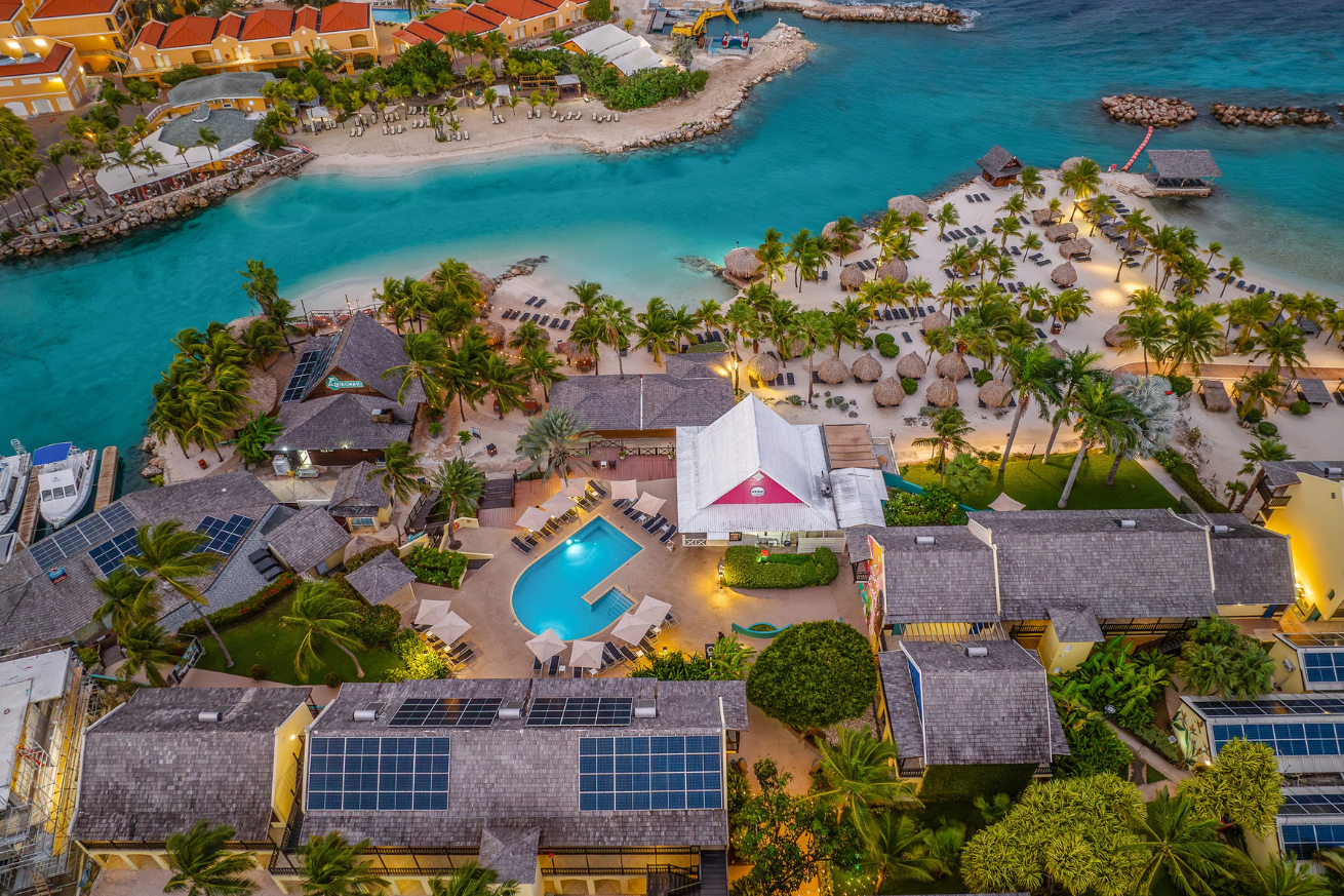 A aerial view of a resort with a pool and a body of water