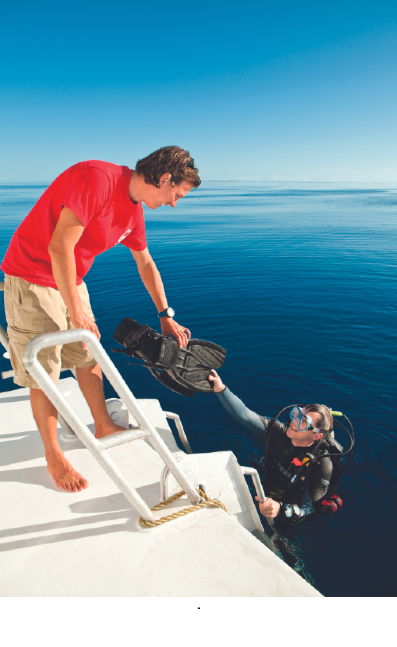A person holding a scuba mask to another person on a boat