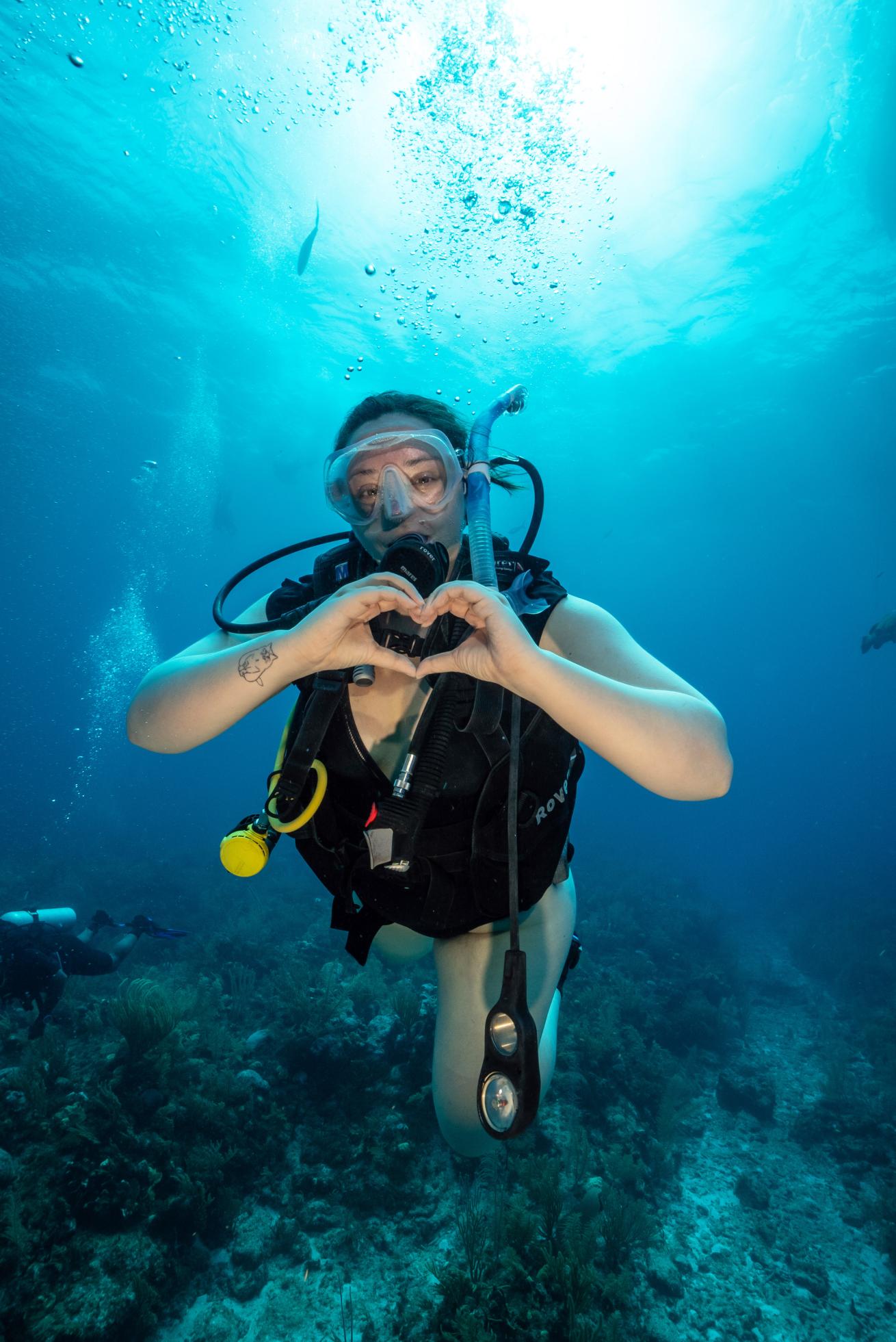 a scuba diver giving a heart sign underwater