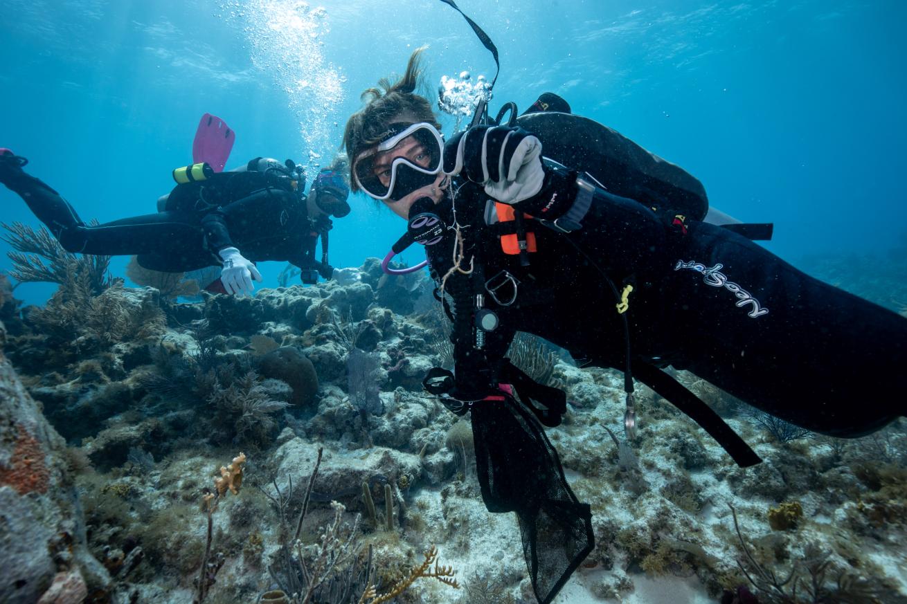 a diver holds up a fishing hook and line she removed from the reef.